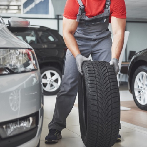 closeup-mechanic-hands-pushing-black-tire-workshop_146671-18343