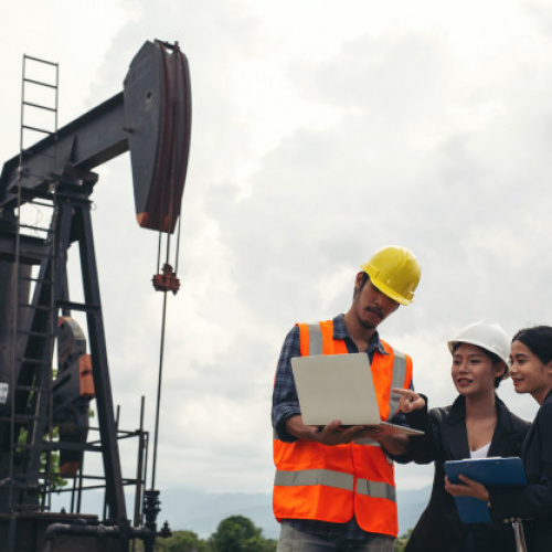 engineering-team-stands-beside-working-oil-pumps-with-sky_1150-19224