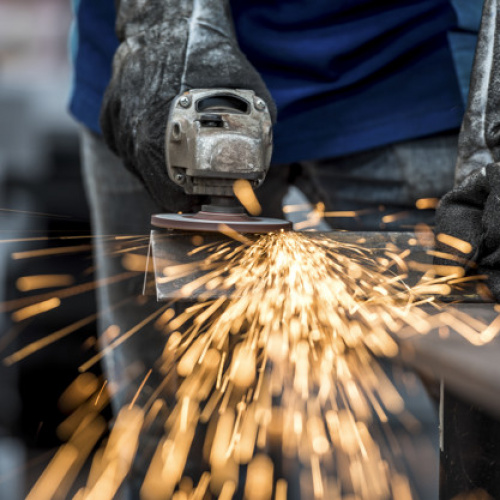 Industrial worker cutting metal with many sharp sparks